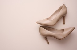 leather beige high heel shoes on a beige background, top view