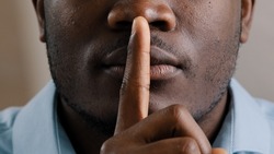 Mysterious unknown male face part african american adult man put finger to lips ask be quiet make gesture silence show secrecy sign keep secret confident information silent forbid tell close up view