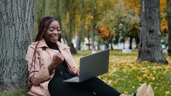 Excited african american woman sitting in autumn park playing online game on laptop gambling competition happy young girl winner celebrating victory enjoying success winning lottery using computer
