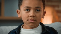 Portrait sad cute little African American boy looking down look at camera. Close up ethnic multiracial multiethnic child orphan pupil son baby schoolboy schoolchild schoolkid upset serious kid face