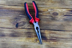 Needle nose pliers with red handles on wooden background