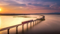 Aerial View The train is running on the bridge Over River Pa Sak Dam Lopburi Thailand and Beautiful sunset 
