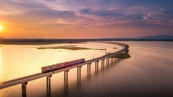 Aerial View The train is running on the bridge Over River Pa Sak Dam Lopburi Thailand and Beautiful sunset 