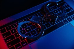 Cyber crime, online piracy and internet web hacking concept. Handcuffs on a keyboard