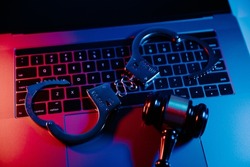Handcuffs and gavel on a laptop. Cyber crime, online piracy and internet web hacking concept