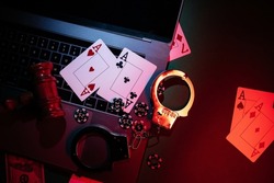 Chips, cards and handcuffs on the laptop. Online casino and gambling concept