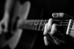 Fingers on guitar strings in black and white