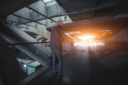 A wide-angle shot of an elegant black bald bearded businessman in a formal suit, walking through a modern futuristic covered pedestrian passageway made of concrete constructions with the light at exit