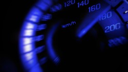 Close up and blurred mile indicator of a speed meter in a car with blue light speed at 180 Km/H in concept racing car