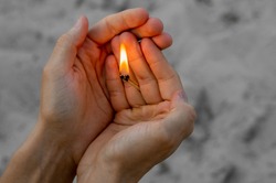 Burning match in hands. The flame from the match pointing to the up. Adult man, sand background.