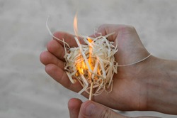 Burning wood filler in the right hand with matchstick, sand background