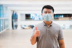 Young asian man wear face shield and mask smiling in shopping mall