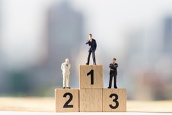 Miniature people: Small businessmen figures standing on wooden podium 1, 2, 3 with cityscape background