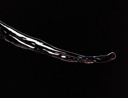 Flow of Crude Oil gasoline pour down over dark background isolated. Black water liquid fall down line. Black Ink, Coffee drink pour splash drop as gold crude oil or sticky water 