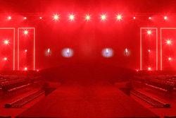 Fashion Show Catwalk Runway Stage in Reddish atmosphere with smoke, spotlight par lighting in red color over hanging construction with black walk way and vdo camera dolly with empty seat, copy space