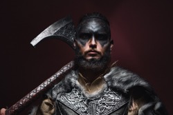 portrait of a Viking man with an axe. A man of 30 years holds a large battle axe on his shoulder. Warrior dressed in an authentic suit