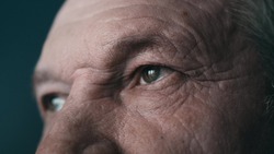 Close-up portrait of an old man. Eyes of an elderly man close-up in profile. A grown man looks away. Cool color. 4K