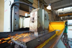 Iron rectangular parts on a flat grinding machine are treated with an abrasive wheel, wide-angle photo.