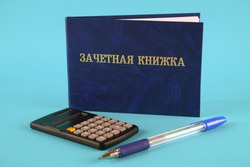 A blue book with an inscription in Russian - a student's record book. Pen, calculator on a blue background. Students Day
