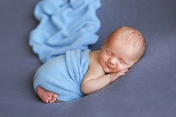 
Newborn baby on a blue surface. Newborn boy is smiling. Beautiful picture of a child. The baby is laughing. The child is wound up. Photoshoot of a newborn 