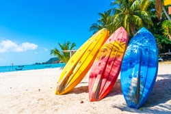 Multi-colored kayaks on a tropical sandy beach. Kayak rental. Tourist entertainment.