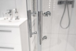 Close-up of chrome handles in a glass shower door. Modern bathroom interior.