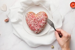 Valentines Day food, happy singles concept. Woman eating heart shaped cake. Table top view. Single young woman celebrating Valentine's Day.