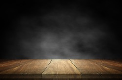 Old wood table top with smoke in the dark background.