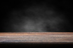 Old wood table with smoke in the dark background. 