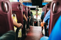 the passengers in the bus during the trip. travelers sit with their backs to the frame, their faces are not visible. the bus is equipped with a TV