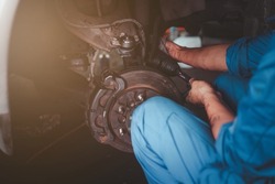 man changes a wheel hub with a wheel bearing in a car, Car disk brake pad replacement service by hand of mechanic man in car garage with flare light effect and copy space