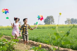 Rural kids playing in  agricultural field with windmill