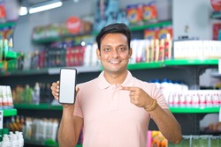 Man pointing at blank mobile phone screen in supermarket