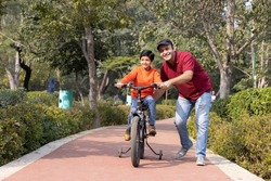 Father teaching son riding bicycle at park
