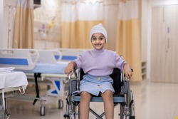 Portrait of sick girl sitting on wheelchair at ward in healthcare center