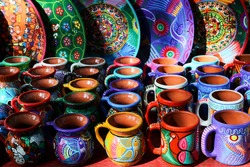 Traditional Mexican souvenirs. Multi-colored ceramic mugs and tableware in the gift shop. Selective focus.