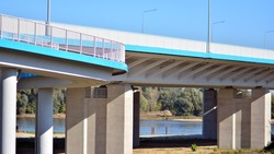 Sunlight penetrates under overpass. Highway overpass bridge concrete structure with columns.