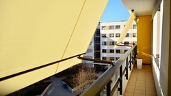Modern architecture building facade with awnings. Balcony with awning opened, covered by sun-shield. 