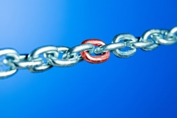 Steel chain with red link on blue backgroud. Weak or problem link concept.