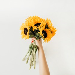 Sunflowers bouquet in women's hands. Flat lay, top view summer floral composition.
