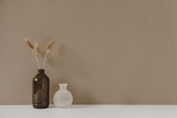 Retro bottle with dry wheat / rye stalk against pastel beige background. Minimal modern interior decoration concept.