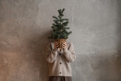 Young pretty woman hold in hands pot with Christmas fir branches. Minimal fashion festive Christmas and New Year celebration concept.