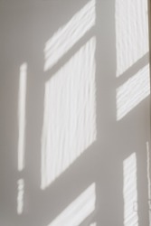 Abstract blurred window sunlight shadows on neutral white concrete wall. Aesthetic sun light shades. Out of focus