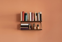 Books stack on hanging shelf. Coral peach wall background. Aesthetic minimal interior design. Reading, education concept with bookshelf
