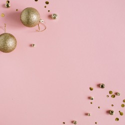 Golden confetti and Christmas toy balls on pink background. Flat lay, top view holiday background.