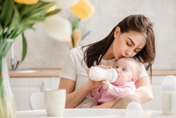 Young woman kiss baby during drinking milk