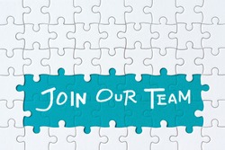 Job recruiting advertisement represented by 'JOIN OUR TEAM' texts on the jigsaw puzzle board. Rows of jigsaw pieces are removed appealing blue green background - metaphor to represent hiring positions