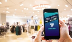 BNPL Buy now pay later online shopping concept.Hands holding mobile phone on blurred store as background