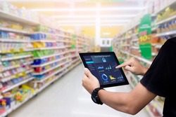 Smart retail management system.Worker hands holding tablet on blurred supermartket as background