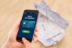 Online bill payment concept.Hands holding mobile phone on blurred Electric bill as background